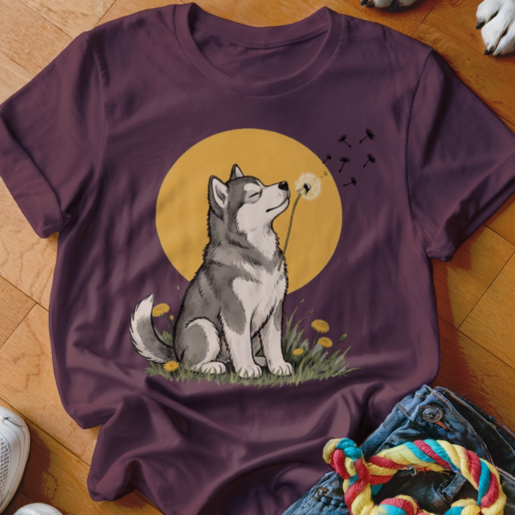 Maroon t-shirt featuring a graphic of a husky dog blowing dandelion seeds in front of a yellow moon.