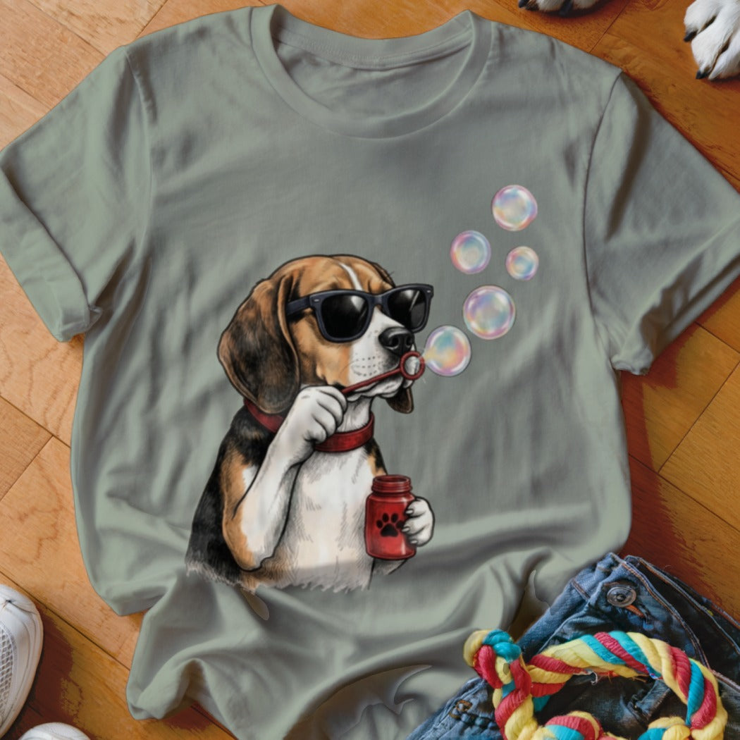 Sage green t-shirt featuring a graphic of a beagle wearing sunglasses and blowing soap bubbles.