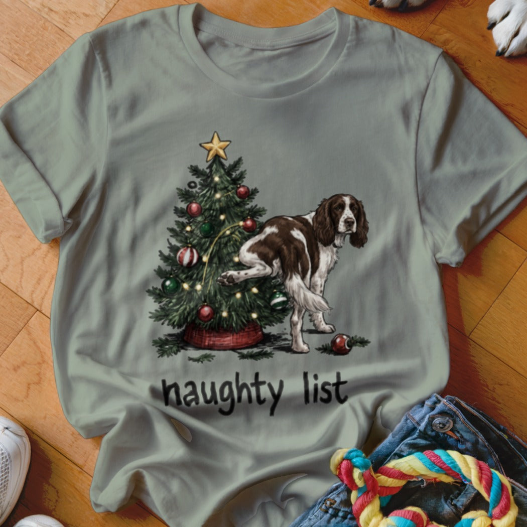 English Springer Spaniel lifting leg on Christmas tree with text "naughty list".