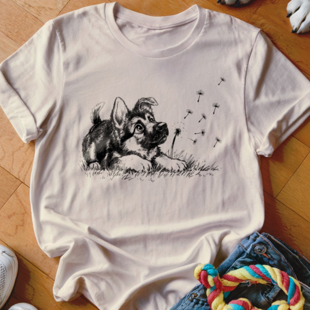 Cream crew-neck t-shirt featuring a black and white sketch of a puppy watching dandelion seeds blow away.