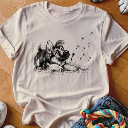 Cream crew-neck t-shirt featuring a black and white sketch of a puppy watching dandelion seeds blow away.