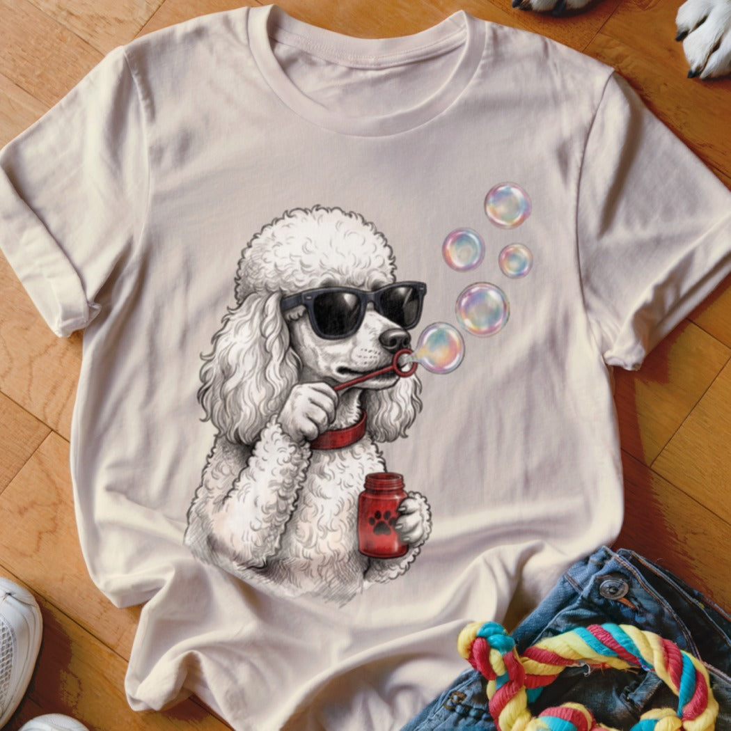 Light-colored crew neck t-shirt featuring a graphic of a white poodle wearing sunglasses and blowing soap bubbles.
