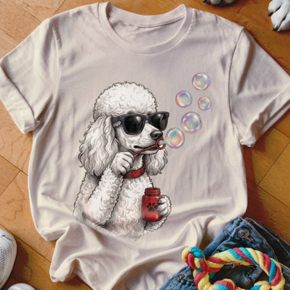 Light-colored crew neck t-shirt featuring a graphic of a white poodle wearing sunglasses and blowing soap bubbles.