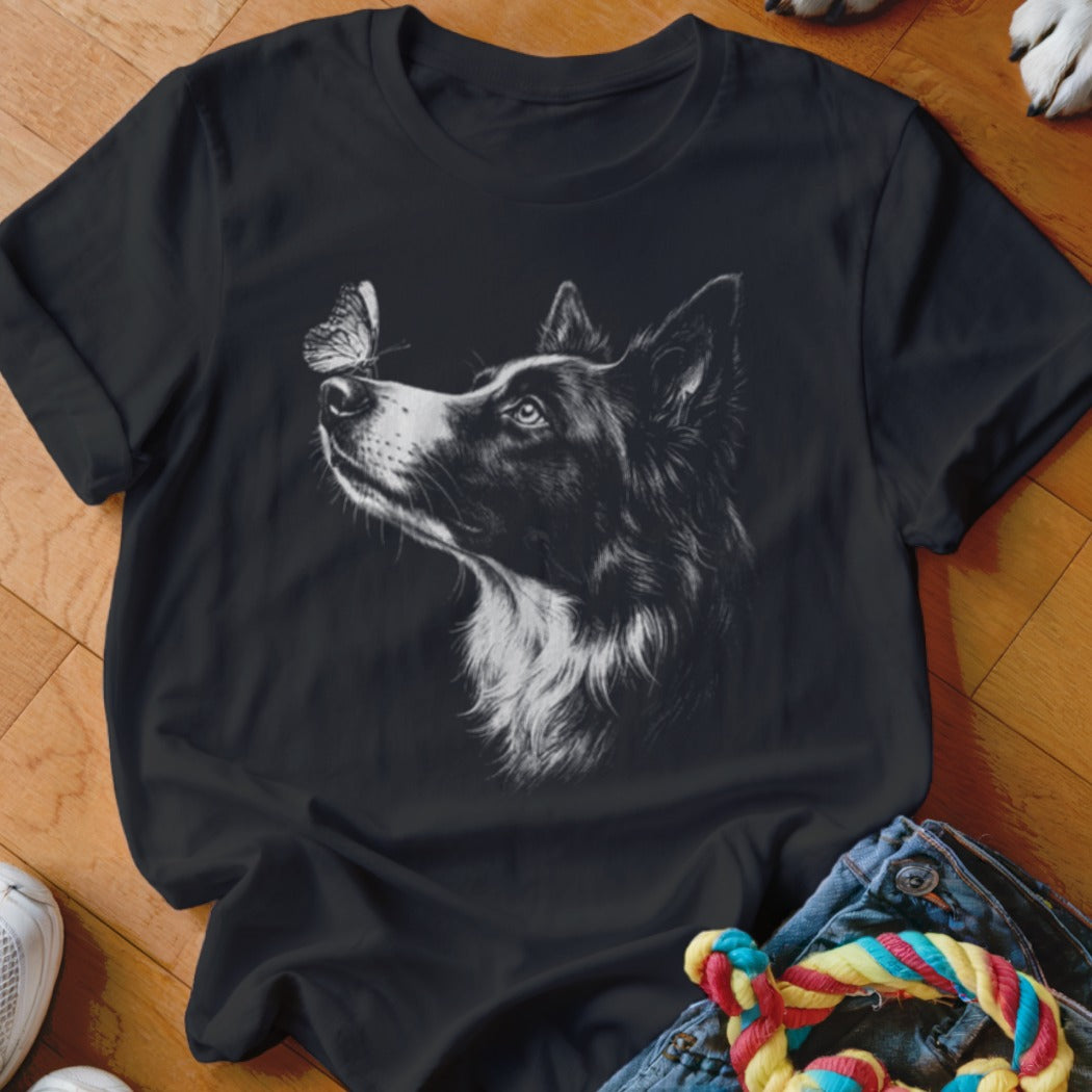 A black crewneck t-shirt featuring a white sketch graphic of a Border Collie looking at a butterfly.