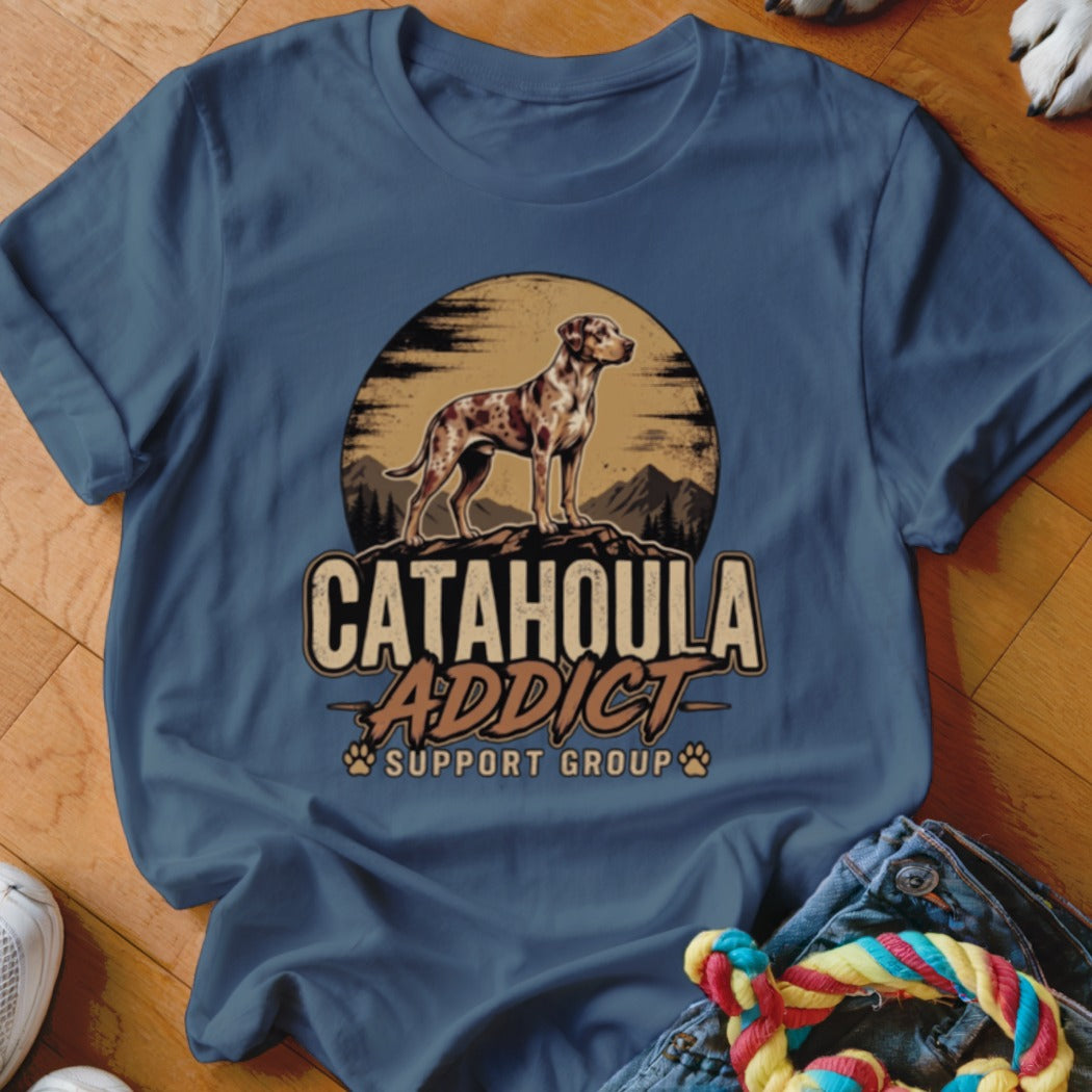 Blue t-shirt featuring a graphic of a Catahoula leopard dog standing before a sunset and mountains with the text Catahoula Addict Support Group.