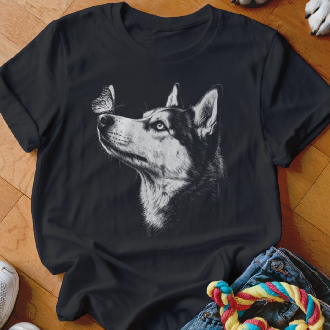 A black crewneck t-shirt featuring a white sketch graphic of a husky looking at a butterfly.