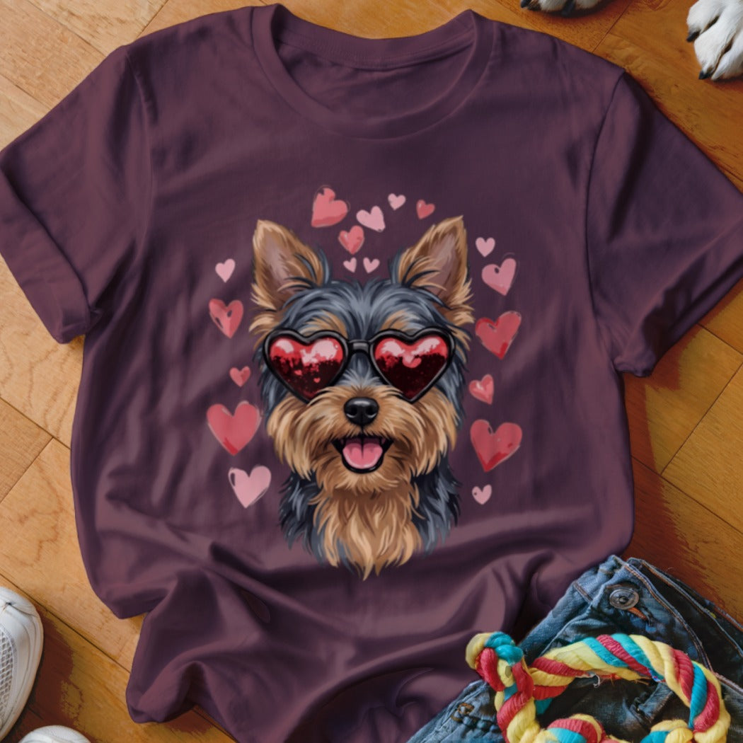 Plum-colored short-sleeved t-shirt featuring a graphic of a Yorkshire terrier wearing heart-shaped sunglasses, surrounded by pink hearts.
