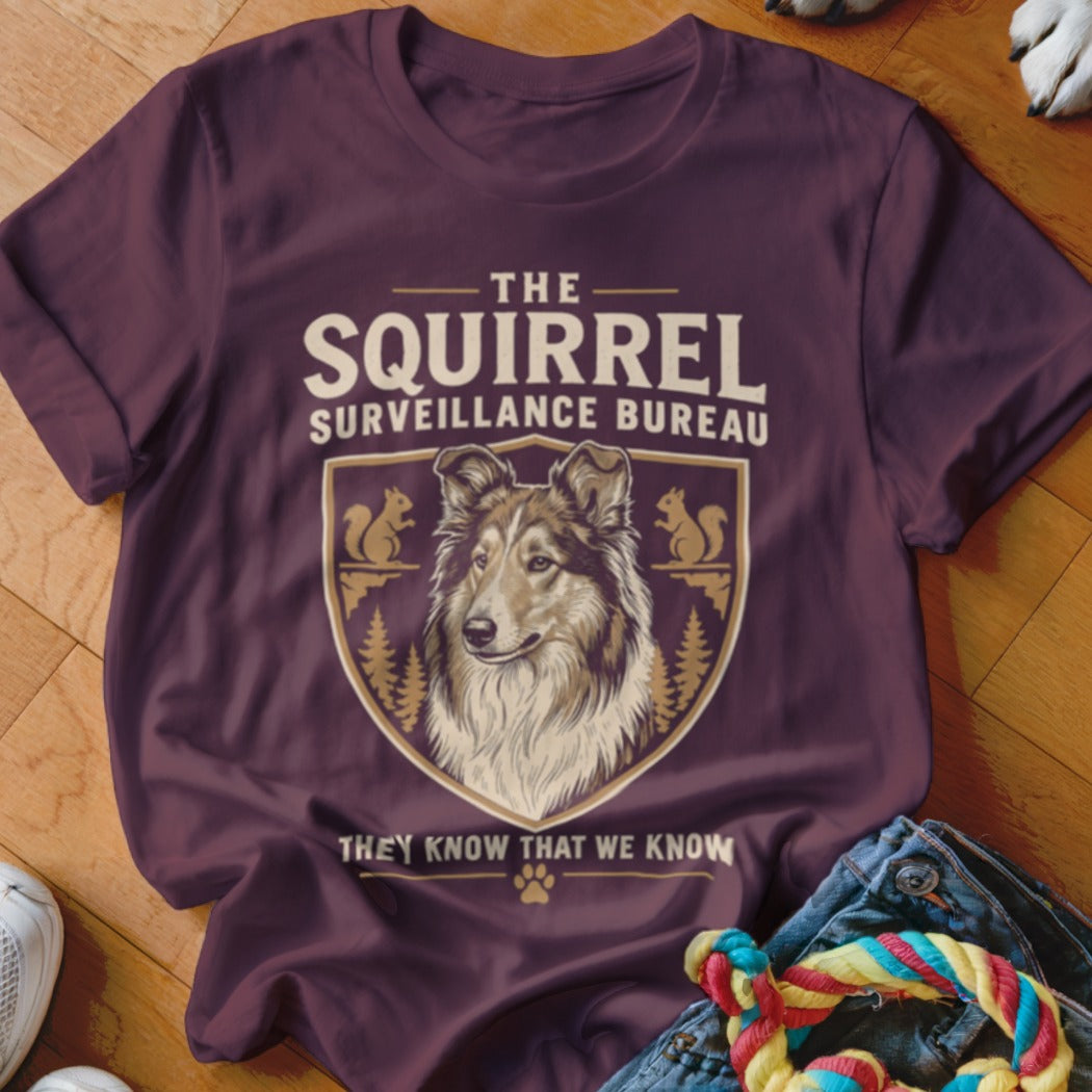 Dark maroon t-shirt featuring a crest with a collie and the text The Squirrel Surveillance Bureau.