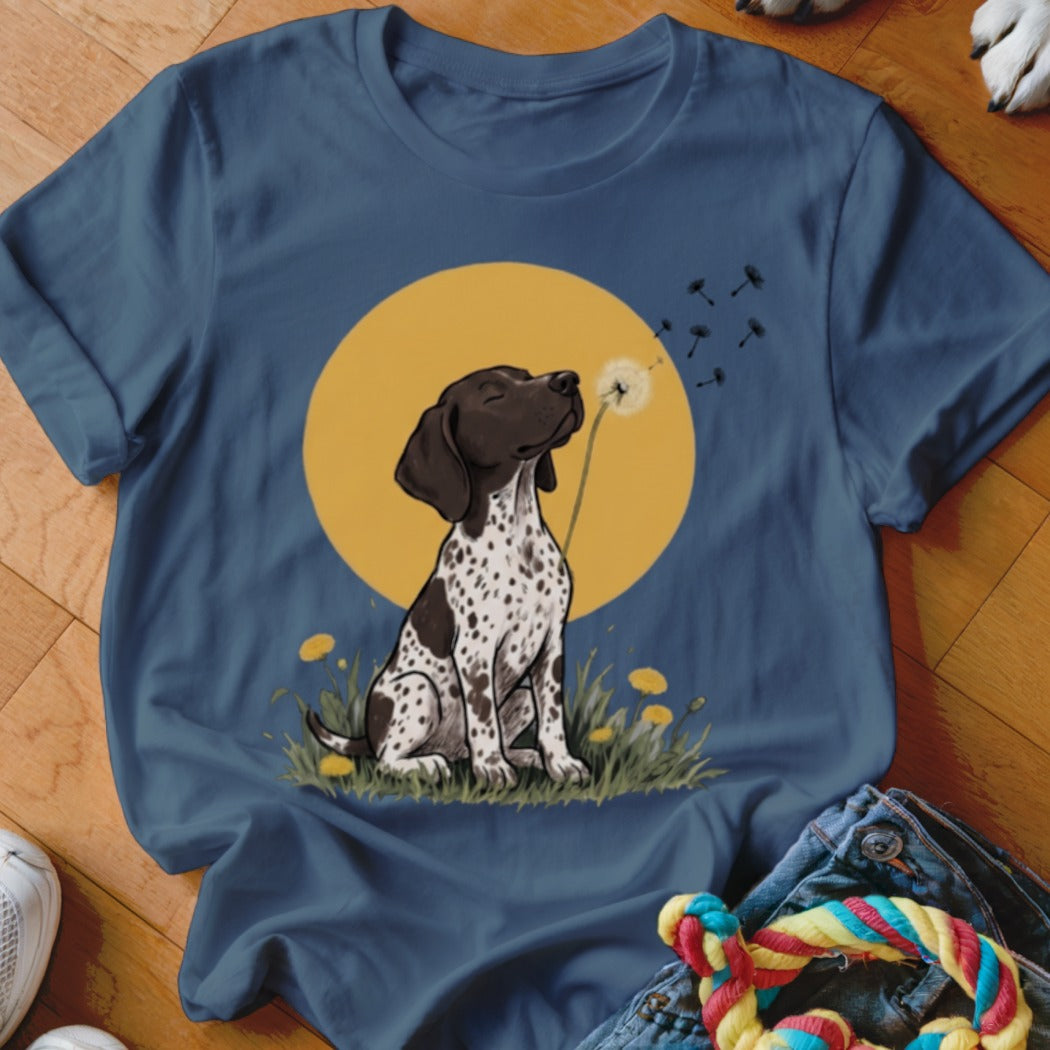 A blue crewneck t-shirt features a graphic of a spotted dog blowing a dandelion.