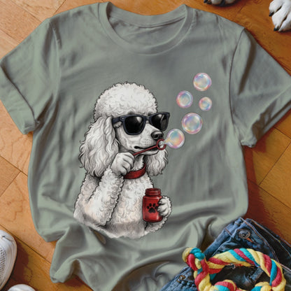 An olive green t-shirt featuring a graphic of a white poodle wearing sunglasses and blowing soap bubbles.