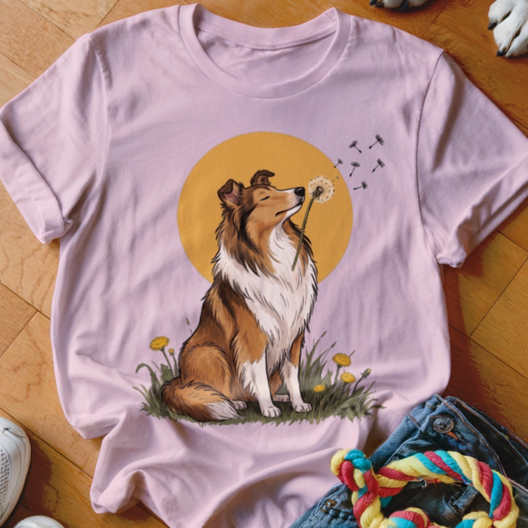 A light pink t-shirt features a graphic of a Collie dog blowing dandelion seeds.
