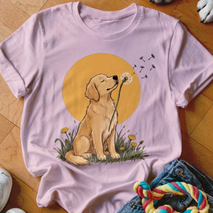 A light pink crewneck t-shirt featuring a graphic of a golden retriever blowing dandelion seeds against a yellow sun.