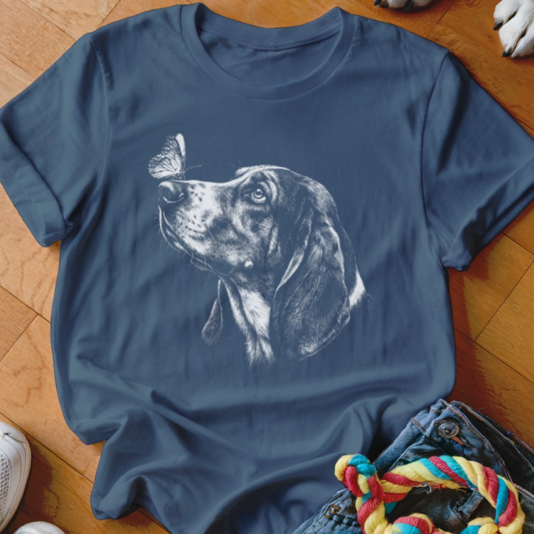 A dark blue crewneck t-shirt featuring a white graphic of a hound dog looking up at a butterfly on its nose.