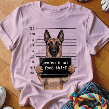 German Shepherd mugshot with "professional food thief" sign on pink t-shirt.