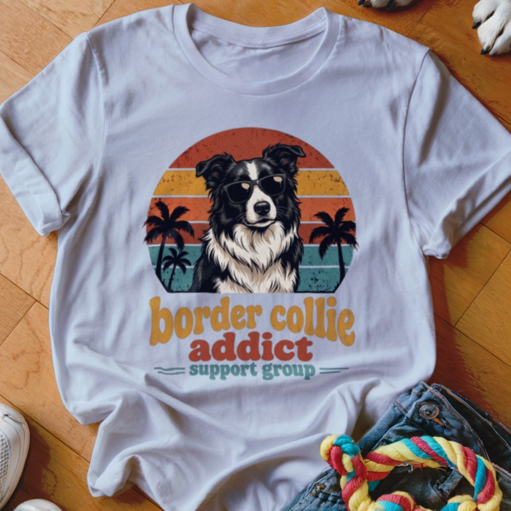 White t-shirt with a graphic of a Border Collie wearing sunglasses, palm trees, and sunset stripes.