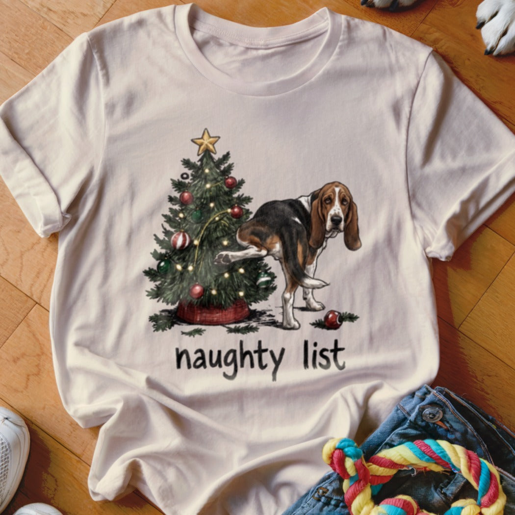 Basset hound lifting leg on Christmas tree with text "naughty list".