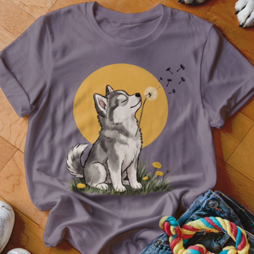 Gray t-shirt featuring an illustration of a husky puppy blowing dandelion seeds against a yellow sun.
