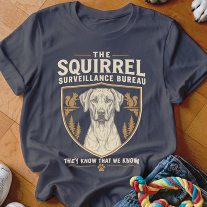 Charcoal t-shirt featuring a crest with a dog, pine trees, squirrels, and text reading The Squirrel Surveillance Bureau.