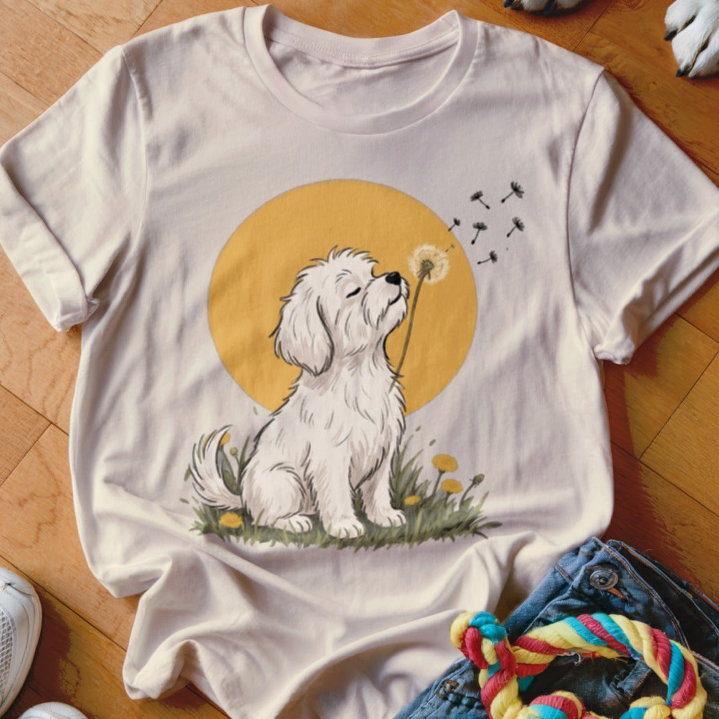 Cream t-shirt featuring an illustration of a white dog blowing dandelion seeds against a yellow circle background.