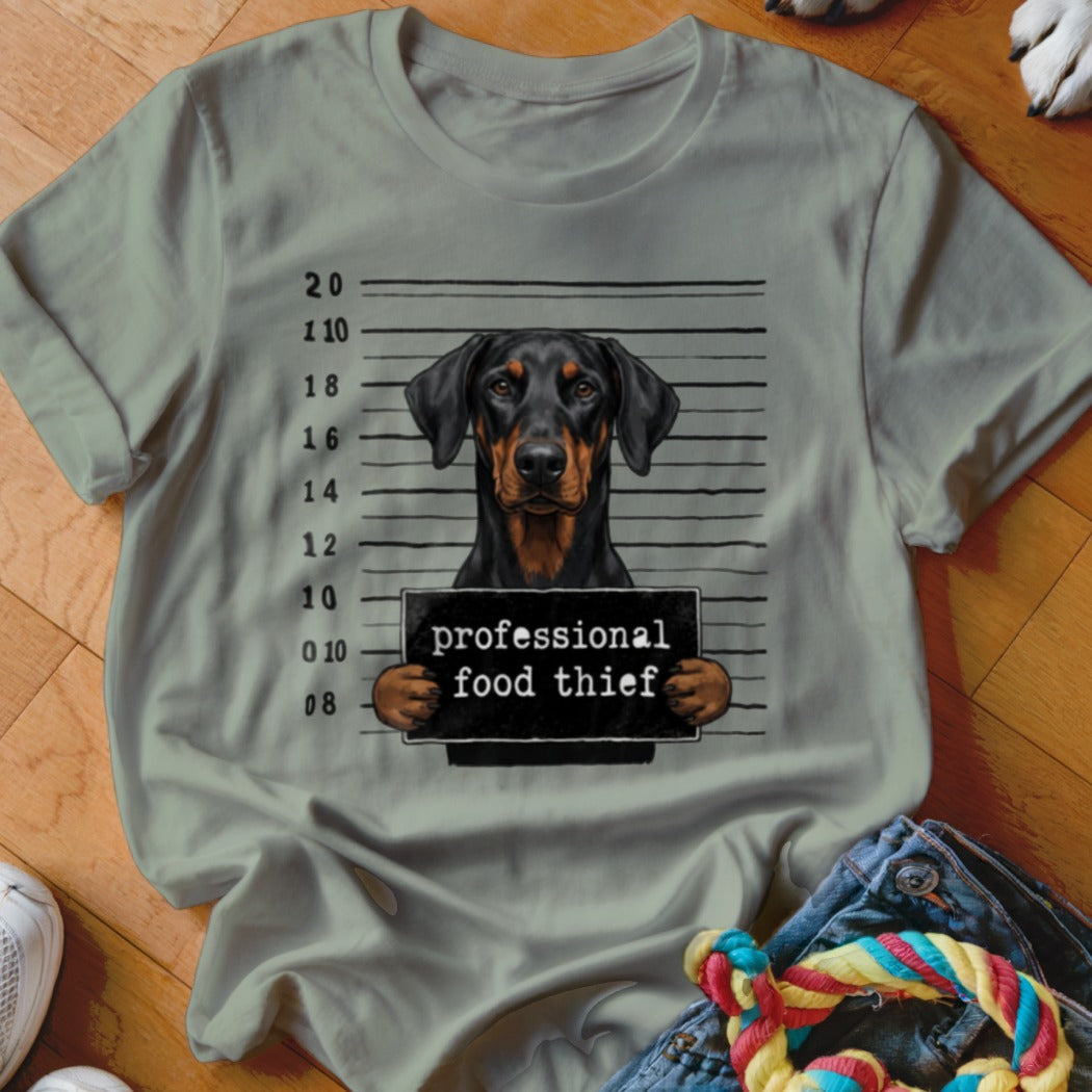 Doberman Pinscher mugshot with sign reading "professional food thief".