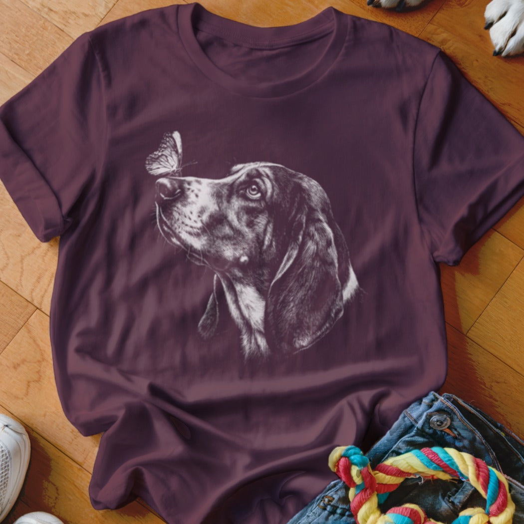 Maroon crewneck t-shirt featuring a white line drawing of a hound dog looking at a butterfly on its nose.
