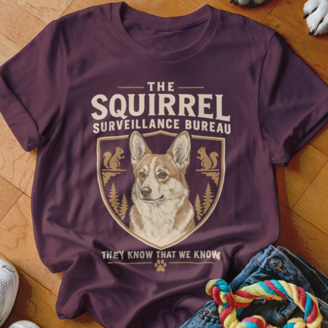 Maroon t-shirt featuring a crest with a corgi and the text The Squirrel Surveillance Bureau.