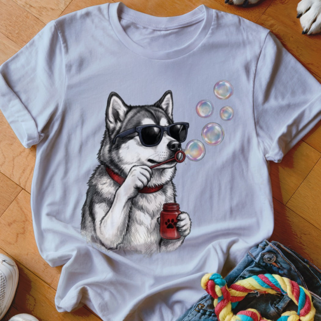 A white t-shirt featuring a graphic of a husky wearing sunglasses and blowing soap bubbles.