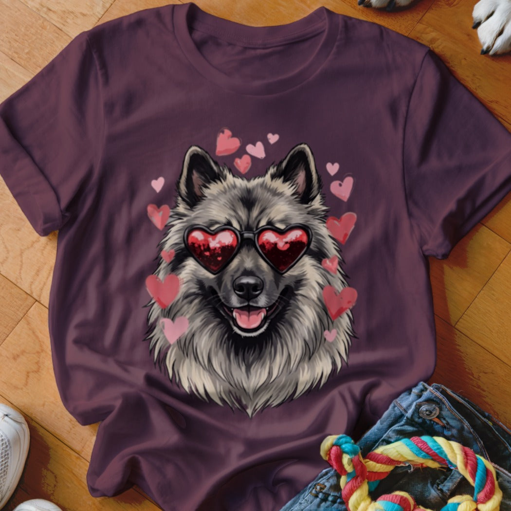 A dark purple t-shirt features a graphic of a fluffy grey dog wearing heart-shaped sunglasses, surrounded by pink hearts.