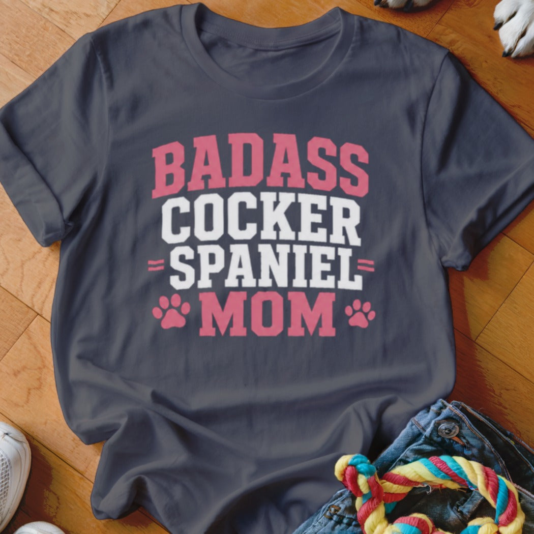 Dark grey t-shirt with "BADASS COCKER SPANIEL MOM" text and paw prints.