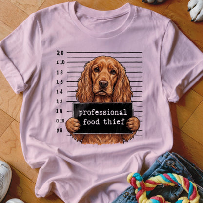 Light pink t-shirt featuring a dog in a mugshot with text "professional food thief".