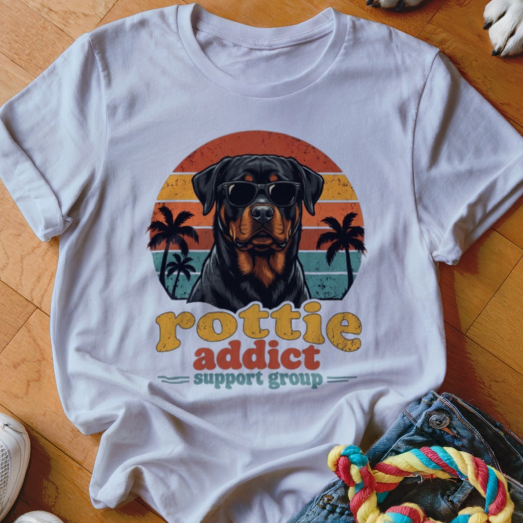 White t-shirt with a vintage graphic of a Rottweiler wearing sunglasses before a sunset and palm trees.