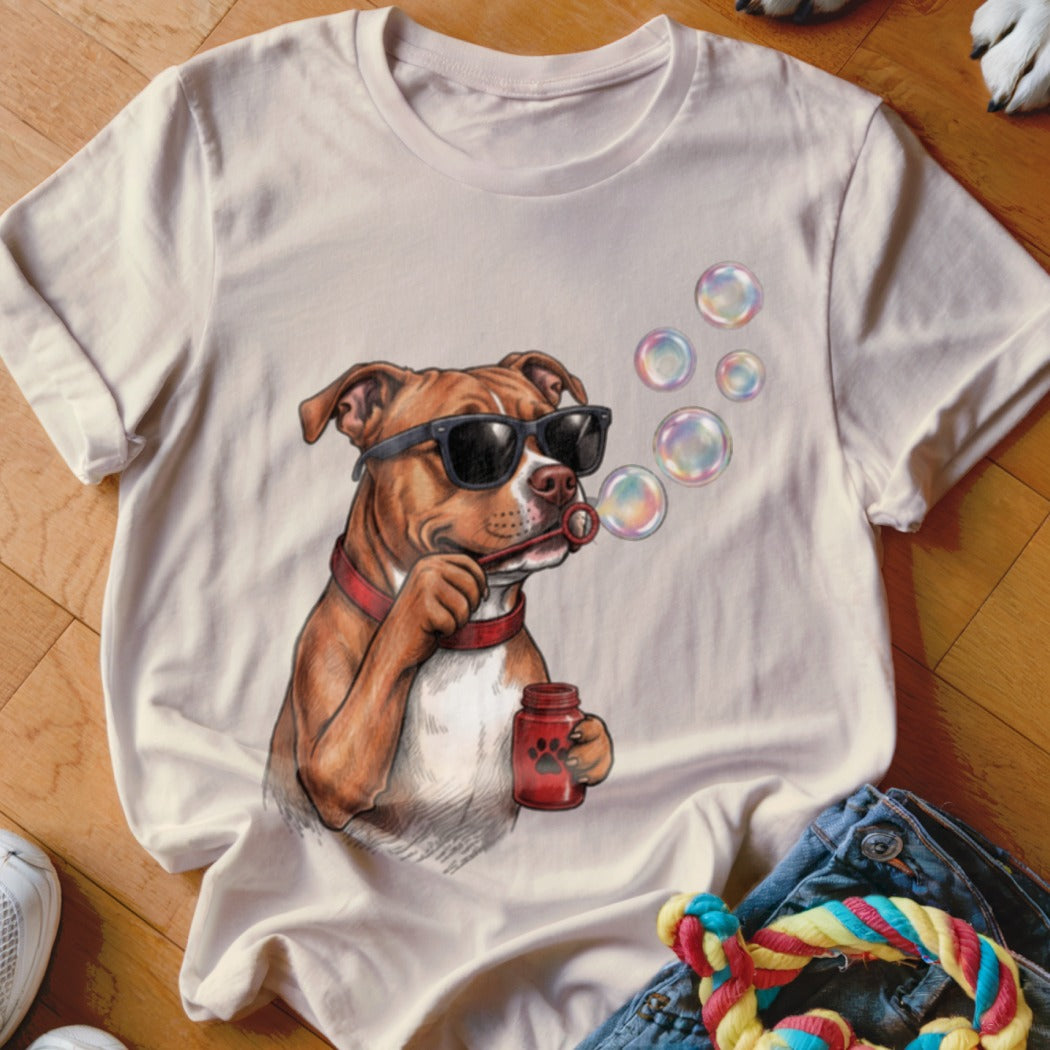 Beige t-shirt featuring a graphic of a brown dog wearing sunglasses and blowing bubbles.
