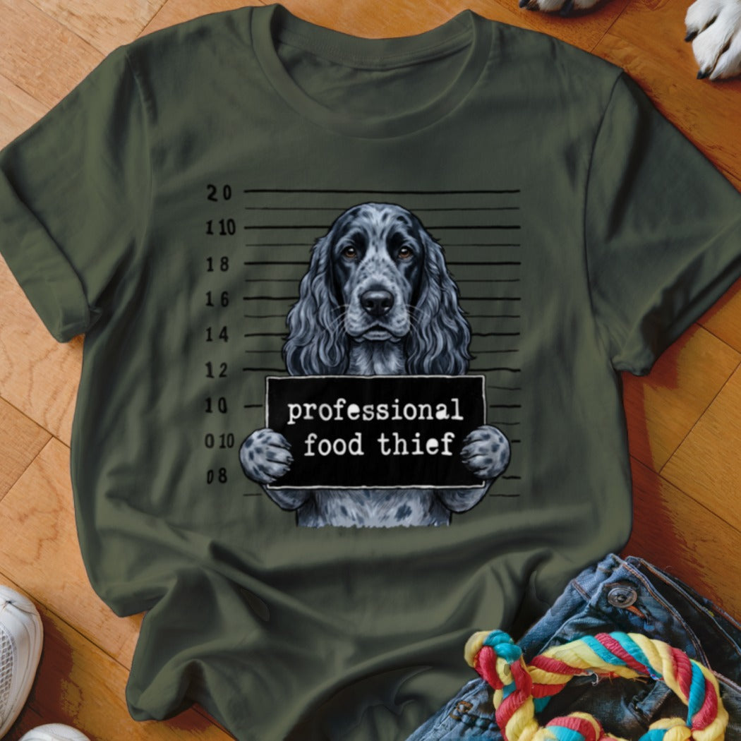 Spaniel dog holding "professional food thief" sign in mugshot style.