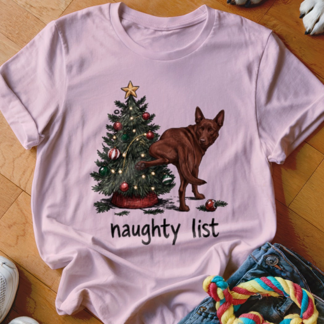 Pink t-shirt with a brown dog near a Christmas tree and the text "naughty list".