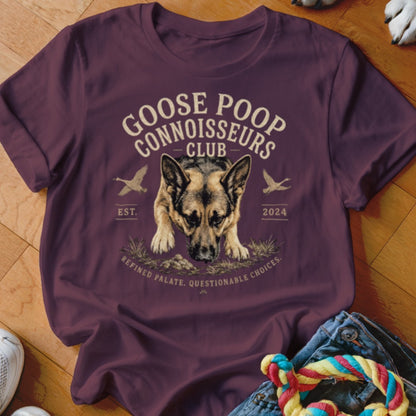 German Shepherd in maroon t-shirt with "Goose Poop Connoisseurs Club" text.