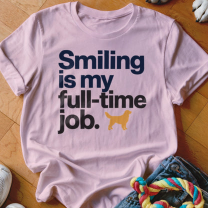 Pink t-shirt with dark blue text "Smiling is my full-time job." and a golden dog silhouette.