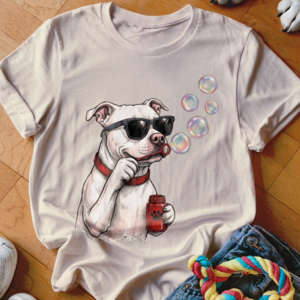 A beige t-shirt featuring a graphic of a white pitbull wearing sunglasses and blowing soap bubbles.
