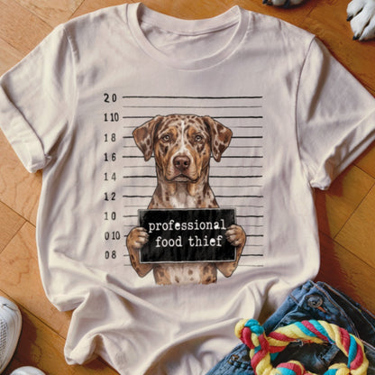 Dog in mugshot wearing a sign that reads "professional food thief".