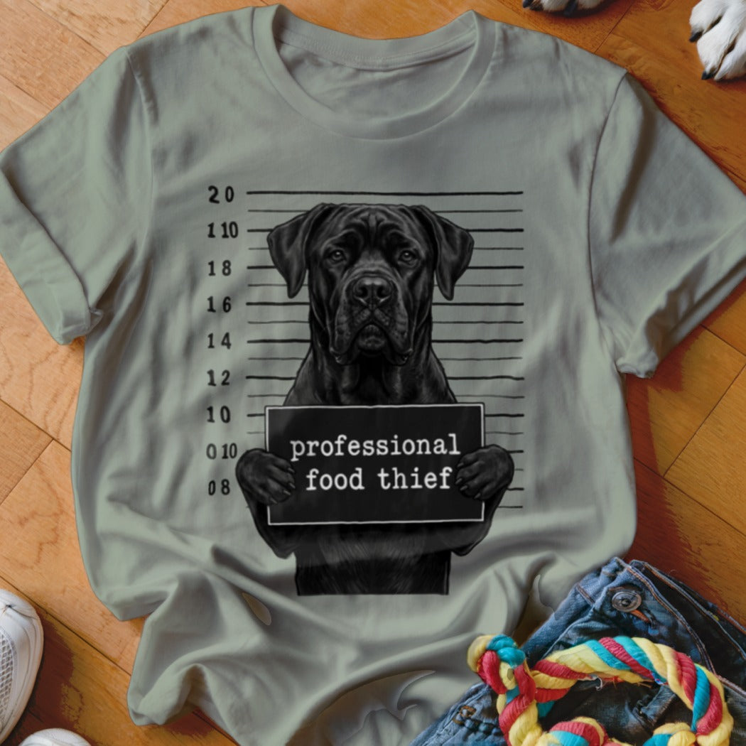 Black dog mugshot with sign that says "professional food thief".