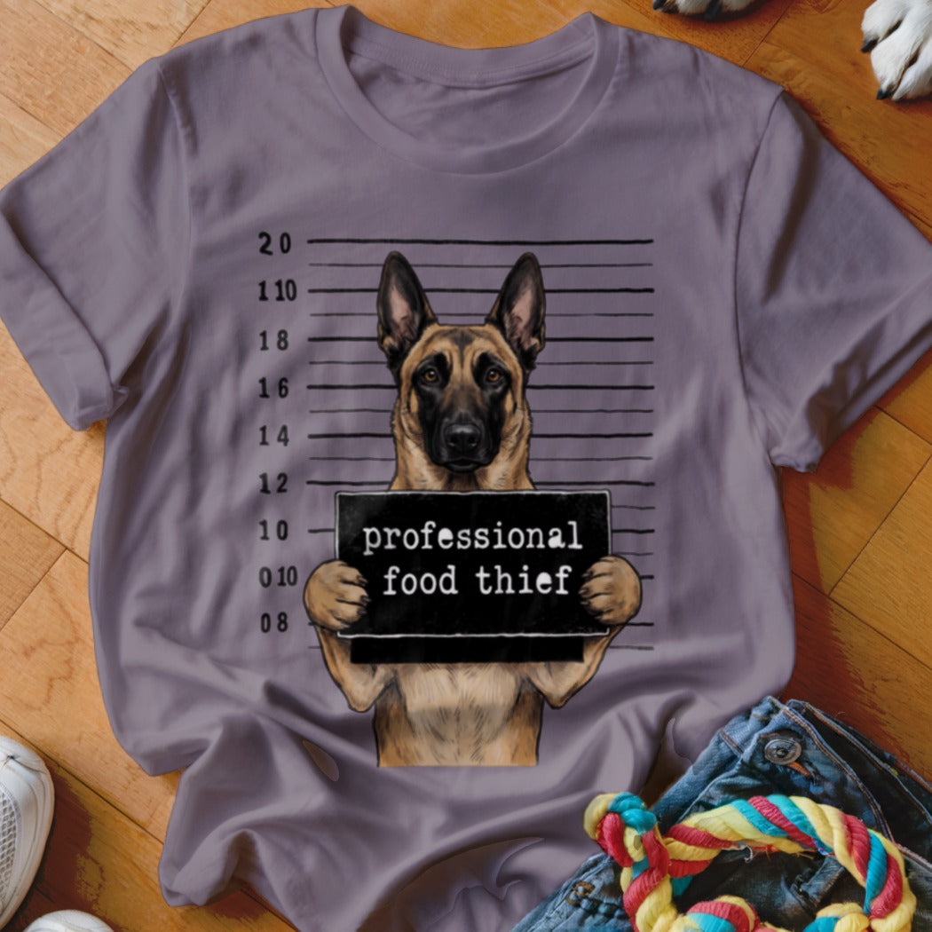 German Shepherd mugshot holding "professional food thief" sign.