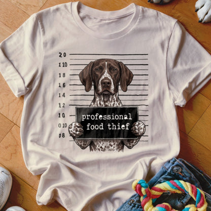 German Shorthaired Pointer mugshot with "professional food thief" sign on a t-shirt.