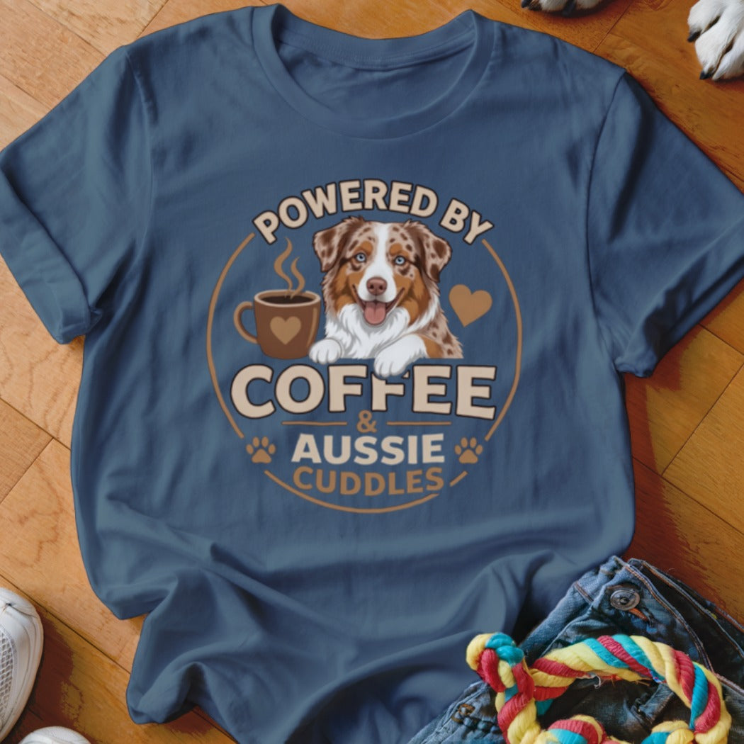 Blue t-shirt featuring a graphic of an Australian Shepherd, a coffee cup, and text reading Powered by Coffee & Aussie Cuddles.