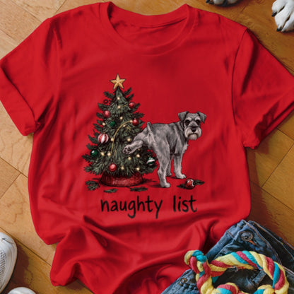 A red t-shirt with a graphic of a Schnauzer lifting its leg on a Christmas tree, with the text "naughty list".