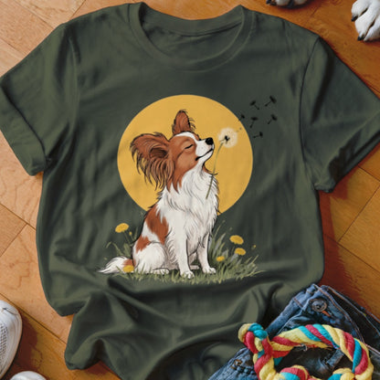 Dark green t-shirt featuring an illustration of a papillon dog blowing dandelion seeds against a yellow sun.