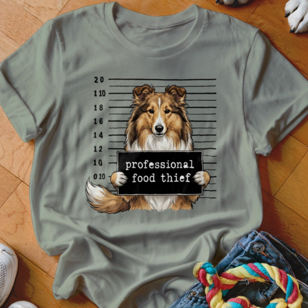 Shetland Sheepdog mugshot with "professional food thief" sign.