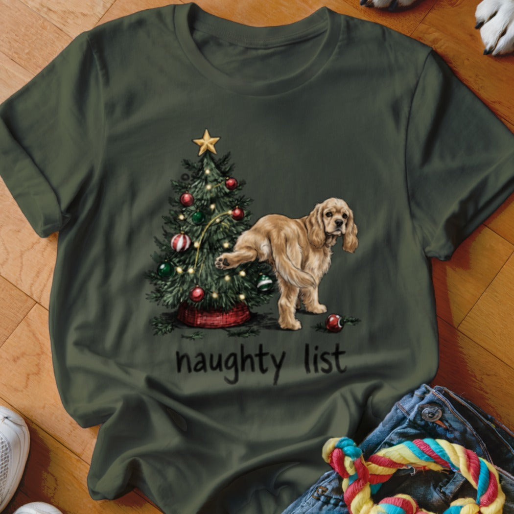 A cocker spaniel lifts its leg on a Christmas tree next to the words "naughty list".
