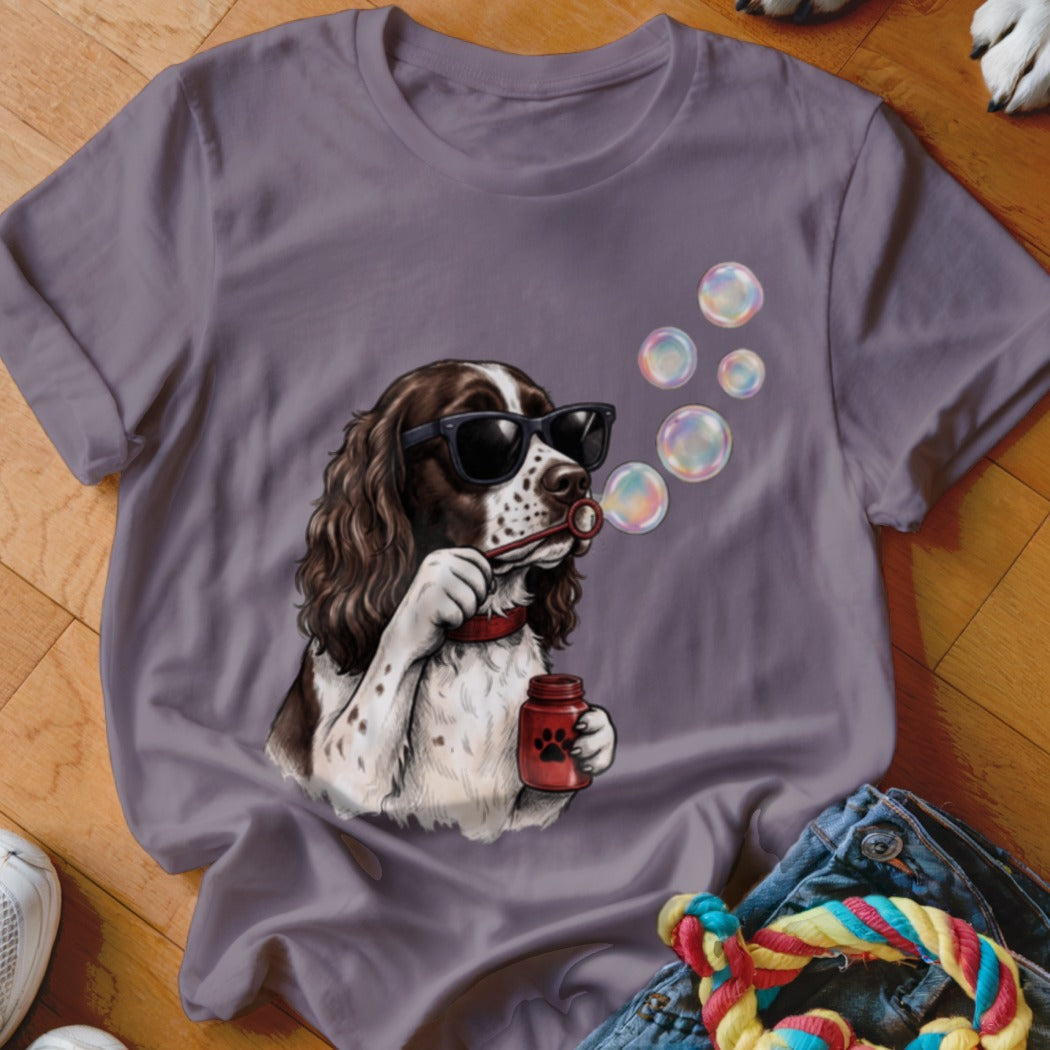 A mauve short-sleeved t-shirt features a graphic of an English Springer Spaniel blowing soap bubbles.