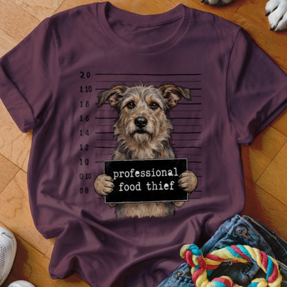 A terrier mix dog holds a sign that reads "professional food thief".