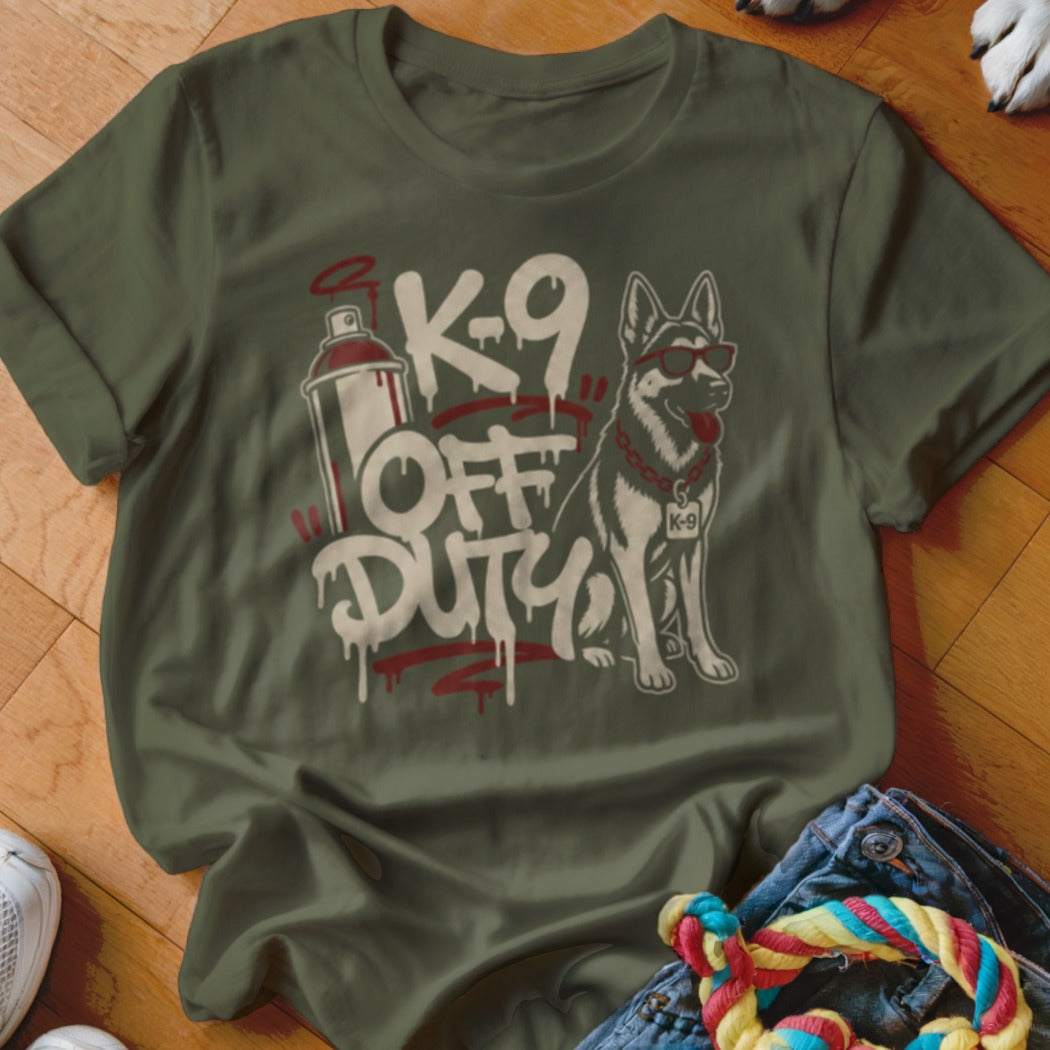 Military dog wearing sunglasses with "K-9 Off Duty" graffiti on a green t-shirt.