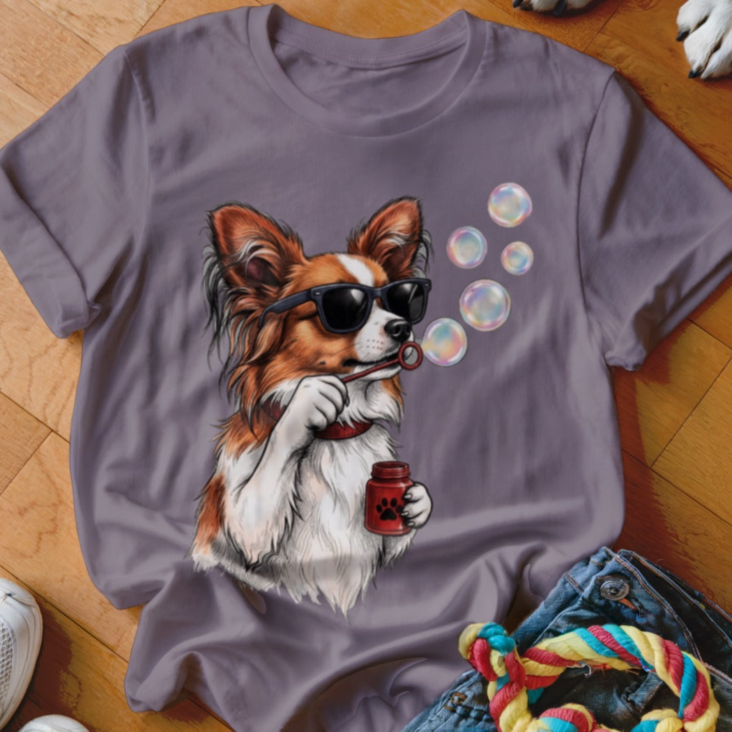 A purple t-shirt featuring a graphic of a brown and white dog wearing sunglasses and blowing soap bubbles.